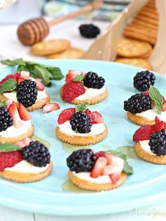 small desserts are arranged on a blue plate with strawberries, raspberries and blackberries