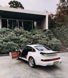 a white car parked in front of a building with its doors open and the door opened