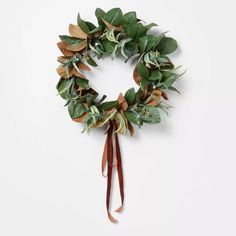 a wreath with green leaves and brown ribbon