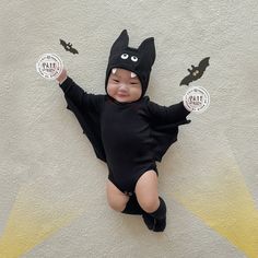 a baby wearing a batman costume laying on the ground