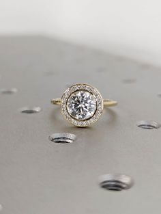 a diamond ring sitting on top of a metal surface with drops of water around it