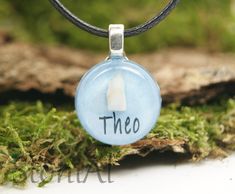 there is a glass pendant with the word thco in it on a mossy surface