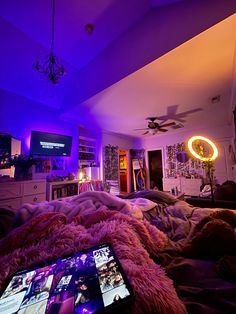 a laptop computer sitting on top of a bed in a room filled with furniture and purple lighting