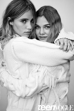 two young women hugging each other while wearing sweaters