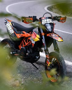 an orange and black dirt bike parked on the side of a road