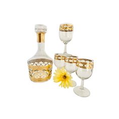 a set of wine glasses and a decanter with a yellow flower in it