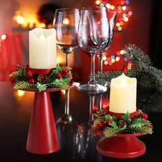 three wine glasses sitting on top of a table next to candles and holly wreaths