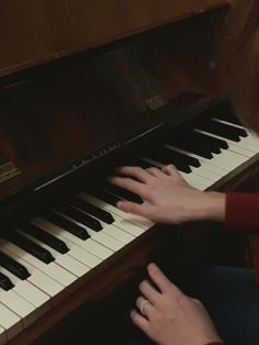 a woman is playing the piano with her hands on it and she is wearing a red sweater