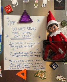 an elf is sitting on top of a refrigerator with paper and magnets attached to it