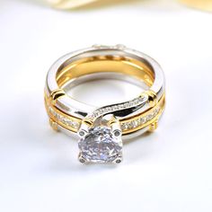 Glistening and glamorous, this ring will win your heart. This eye-catching interchangeable ring set features an enchanting round stone and rows of smaller stones embellish the engagement ring in profile. Additional stones are set into the yellow gold tone matching wedding bands. Gleaming with your love, this slender wedding set is a true reminder of your everlasting love.Carat Weight: 3.5 ctStone Size: 8 mmStone Type: Jeulia® StoneNumber of Stones: 1 Stone Color: Diamond WhiteStone Shape: RoundC Gold Cubic Zirconia Round Bridal Sets, Gold Stackable Rings With Center Stone, Gold Bridal Sets With Center Stone For Anniversary, Gold Stackable Rings With Center Stone In Round Band, Gold Stackable Rings With Center Stone For Anniversary, Gold Diamond Stackable Rings With Center Stone, Elegant Gold Stackable Rings With Round Stones, Gold Diamond Ring With Round Stone For Promise, Gold Promise Diamond Ring With Round Stone