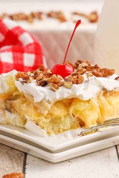 a white plate topped with a piece of cake covered in whipped cream and pecans