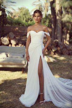 a woman in a white wedding dress posing for the camera with her legs slited