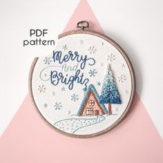 a hand embroidered christmas ornament hanging on a pink and white background with snowflakes