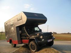 a black and red truck parked on the side of a road next to a field