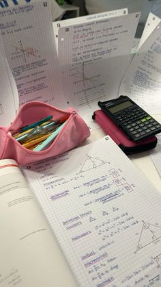 a calculator, notebooks and pencils are on the table with papers