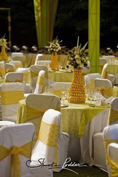 tables and chairs covered in yellow linens at a wedding