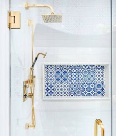 a blue and white tiled shower with gold fixtures