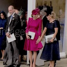 two women in pink dresses standing next to each other near men and women dressed in suits