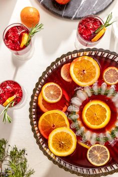 a table topped with glasses filled with liquid and sliced oranges