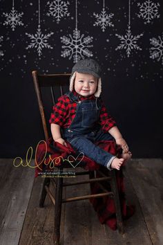 a little boy sitting in a chair with snowflakes on the wall behind him