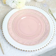 a pink and white plate sitting on top of a table next to a vase with flowers