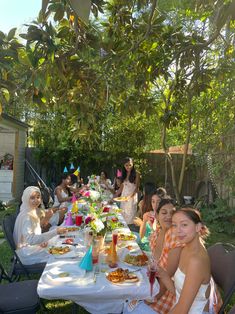 a group of people sitting around a table with food