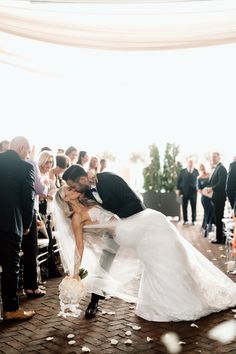 a bride and groom kissing at the end of their wedding ceremony with confetti falling all around them