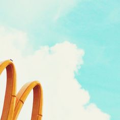 a mcdonald's sign is shown in front of a blue sky with white clouds