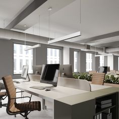 an empty office with desks and chairs in the foreground, large windows on both sides