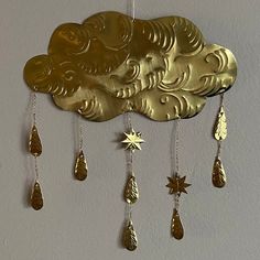 a gold clock hanging from the side of a wall with stars and clouds on it