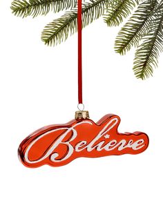 a red ornament hanging from a christmas tree with the word believe on it