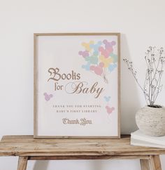 there is a sign that says books for baby on the table next to a potted plant