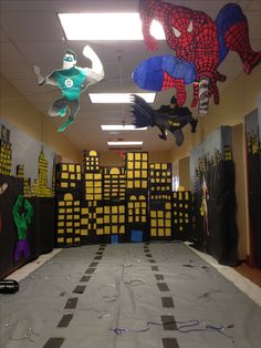 an office decorated for halloween with spiderman, batman and green lanternes hanging from the ceiling