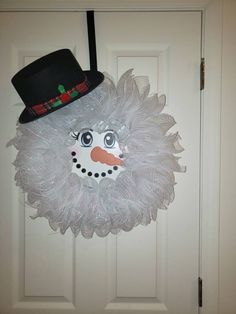 a white door with a snowman wreath hanging from it's side and a hat on top