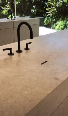 a kitchen counter with two black faucets on it