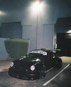 a black sports car parked in a parking lot next to a tall plant with the word south west written on it