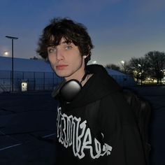 a young man in a black hoodie is looking at the camera with his eyes closed