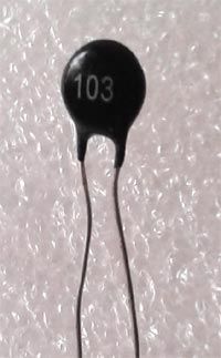 an electronic capacitor with the number 103 printed on it's back side