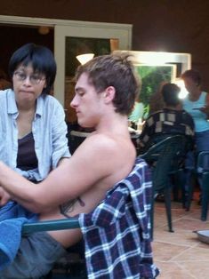 two people sitting at a table with food in front of them and one person holding a cell phone