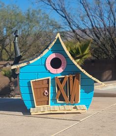 a blue house shaped like a boat with a pink eyeball on it's face