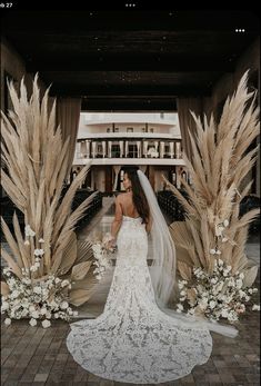 a woman in a wedding dress standing next to tall grass