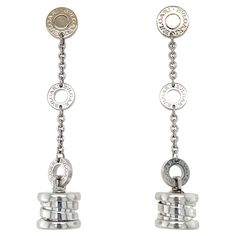 From the classic B.zero1 Collection, these earrings contain a button top suspending a dangling drop with hoop and chain detail, all engraved Bulgari. Measurements: 2 inches long. Stamp: MADE IN ITALY 750 (Italian hallmark for Bulgari) Weight: 10.80 grams Gold Dangle Earrings, Button Top, Gold Earrings Dangle, Made In, Jewelry Earrings Dangle, Dangle Earrings, In Italy, Jewelry Earrings, White Gold