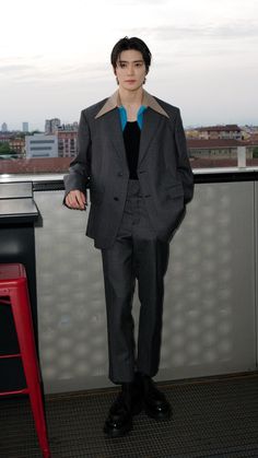 a man in a suit standing next to a red chair on top of a roof