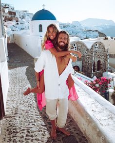 a man carrying a woman on his back while standing in front of a white building