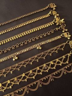 several different types of gold chains on a black surface