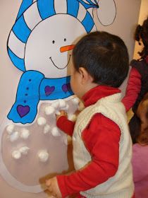 a little boy standing in front of a snowman sign with marshmallows on it