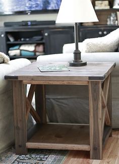 a wooden table with a lamp on top of it in front of a white couch