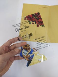 a hand holding up an envelope with the disney princess and prince wedding card on it