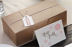 a brown box with a tag on it sitting next to a white and pink card