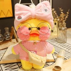 a yellow stuffed animal wearing glasses and a pink sweater with a bow on it's head